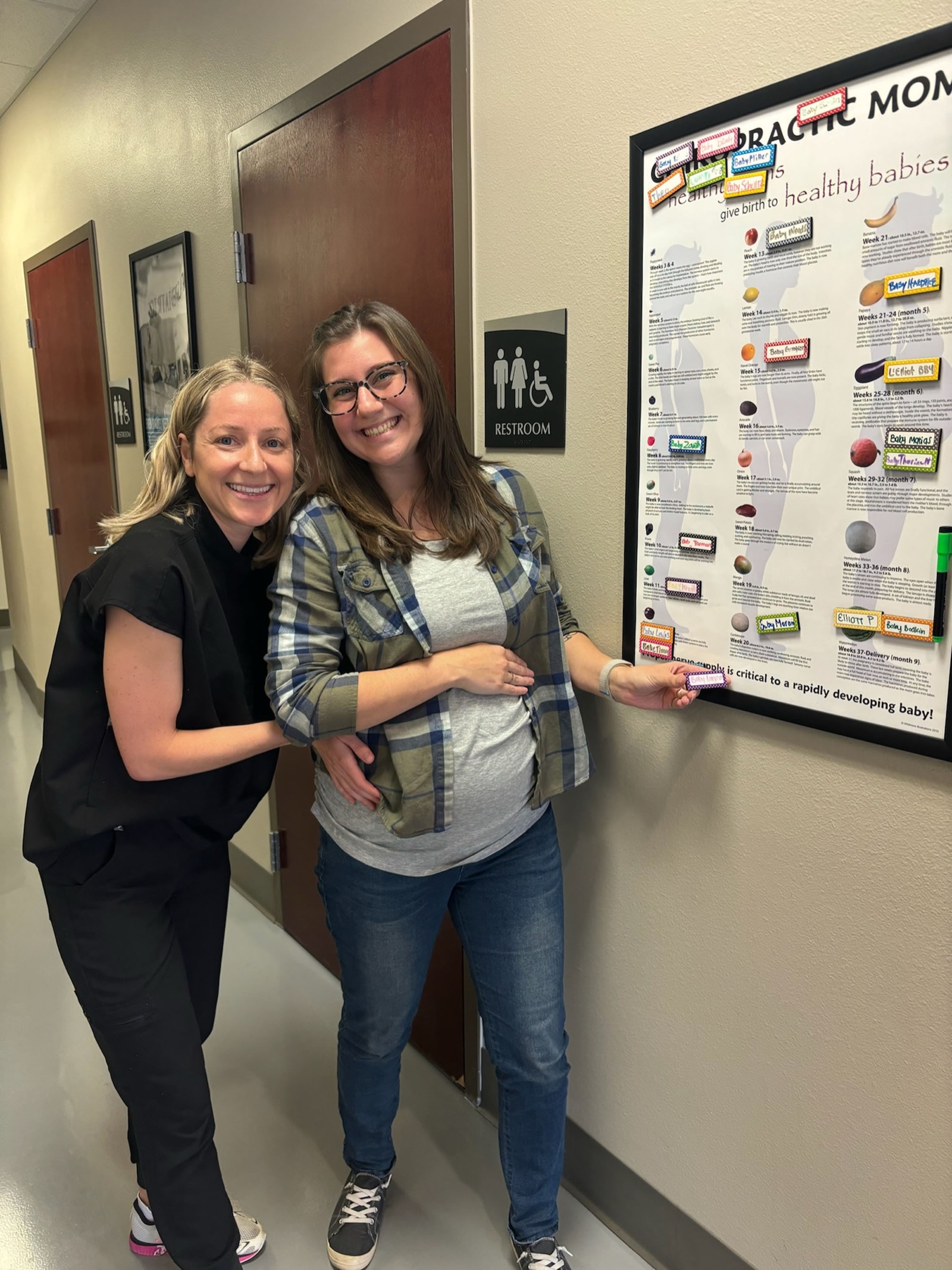 Dr. Laura Swaim with a pregnant patient at the Chiropractic Moms wall.