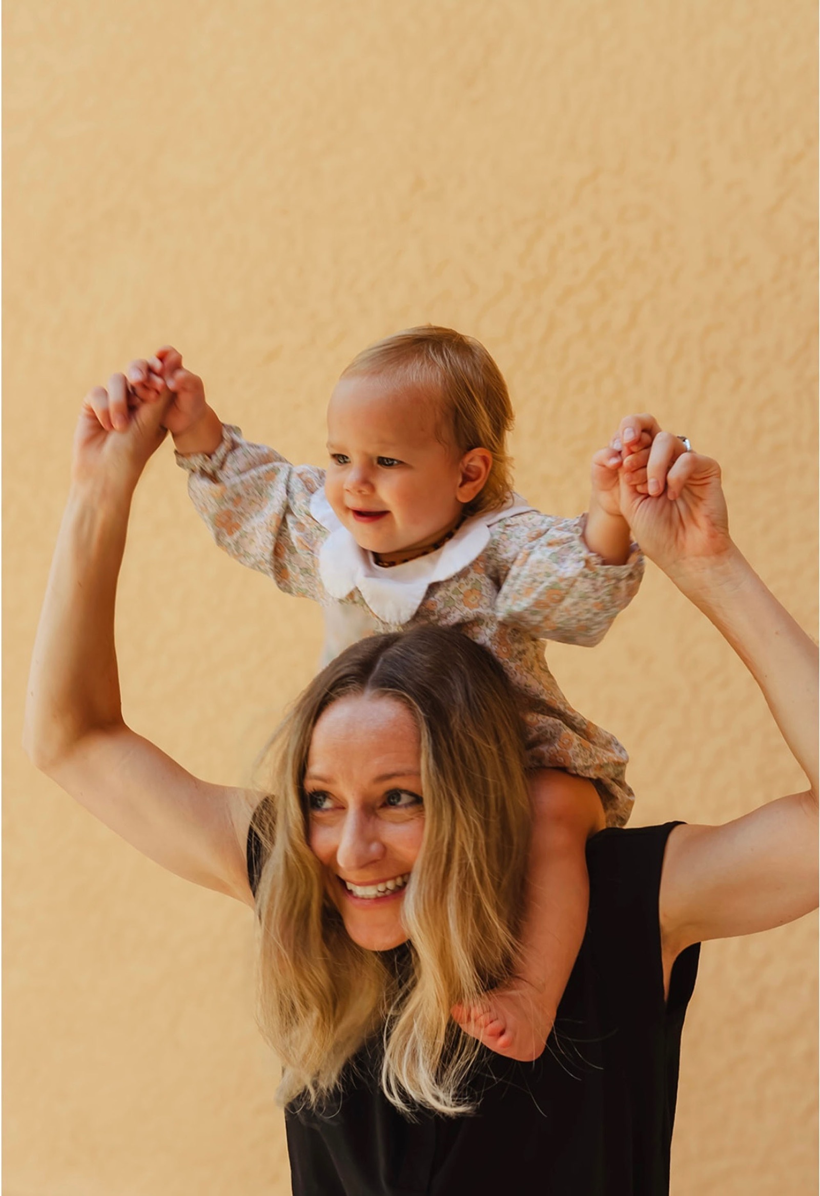 Dr. Laura Swaim smiles with her daughter on her shoulders.