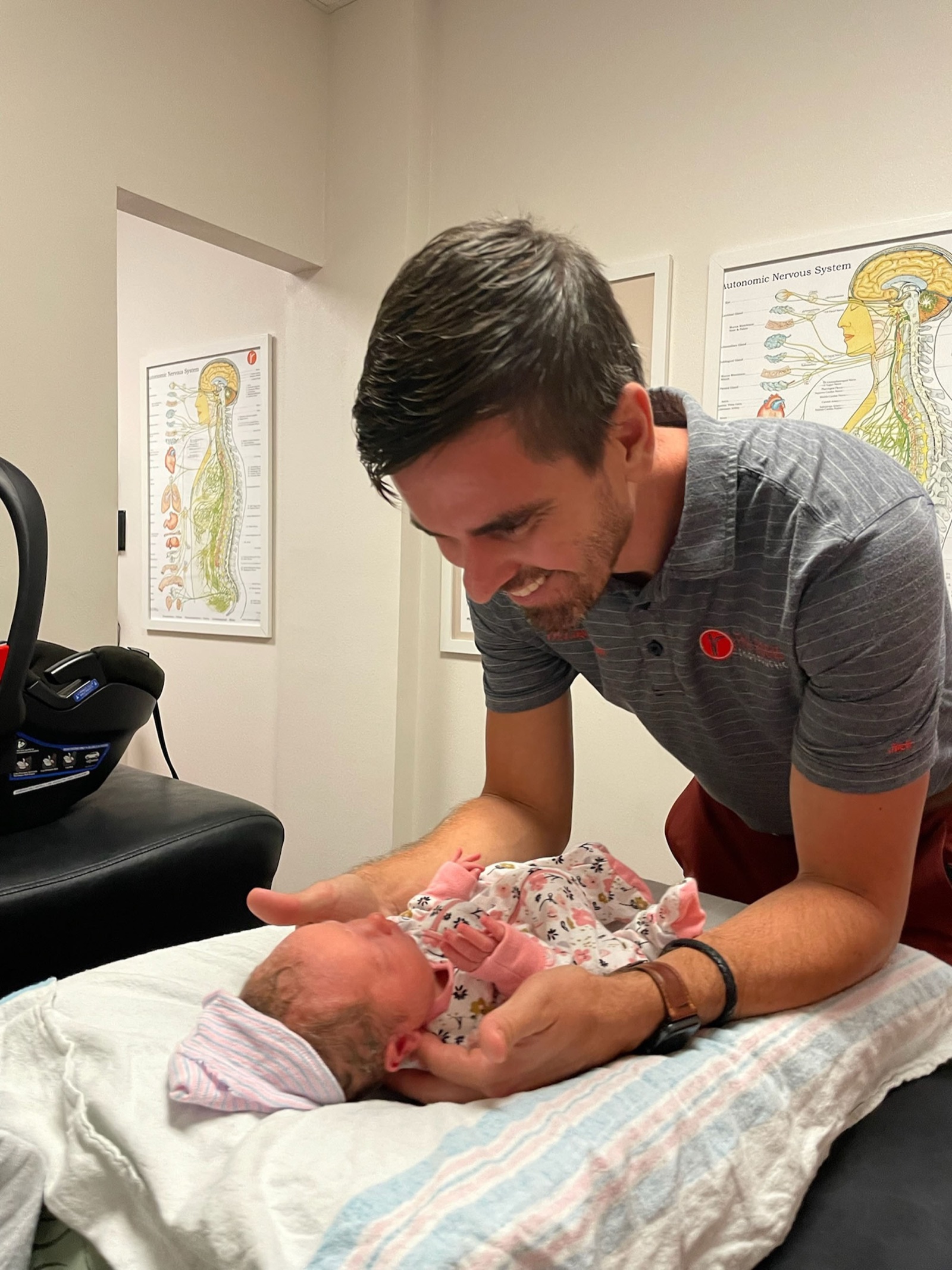 Dr. Logan Swaim holds eye contact with a newborn before an adjustment.