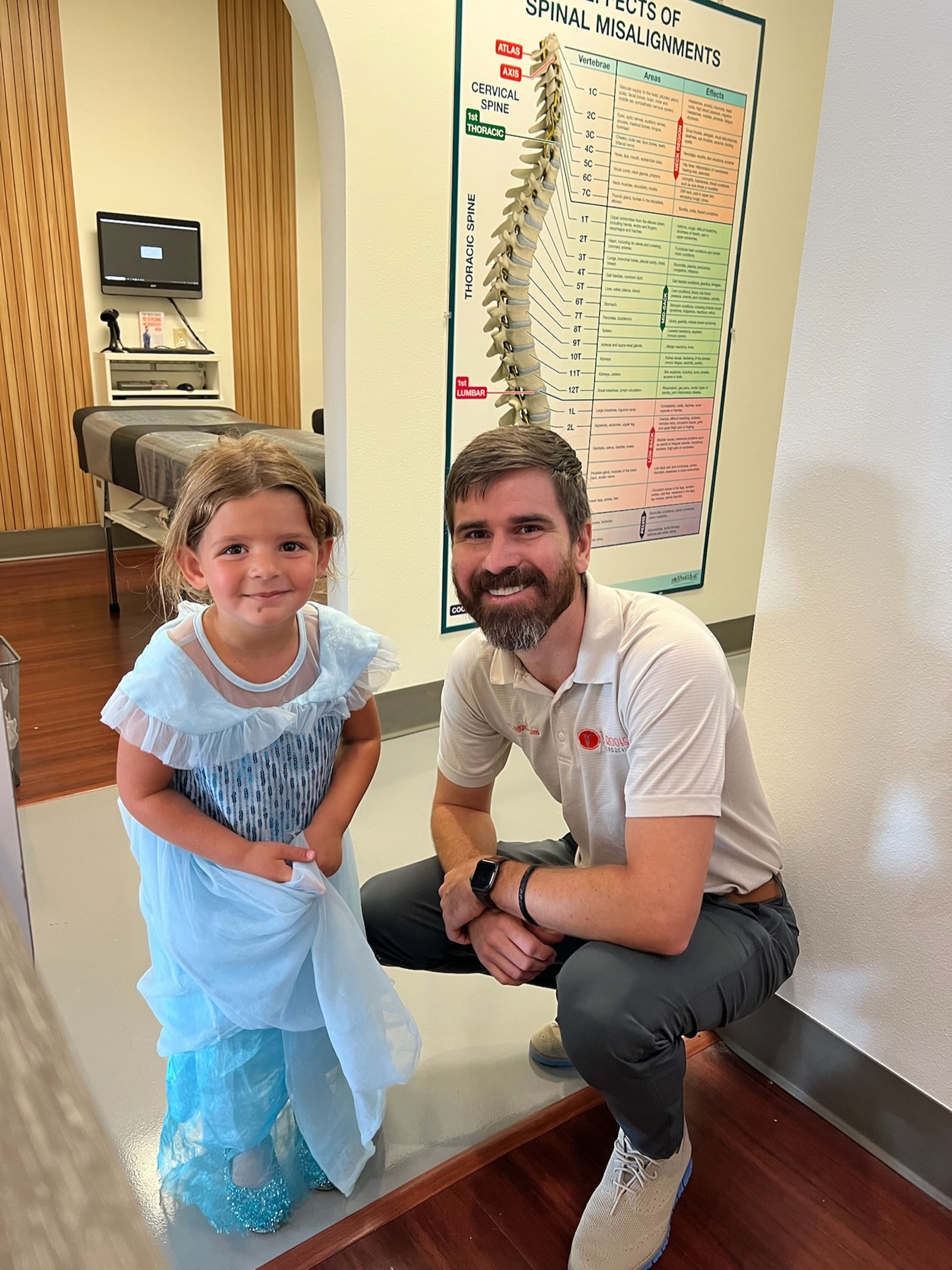 Dr. Logan kneels beside a young patient in a princess dress.