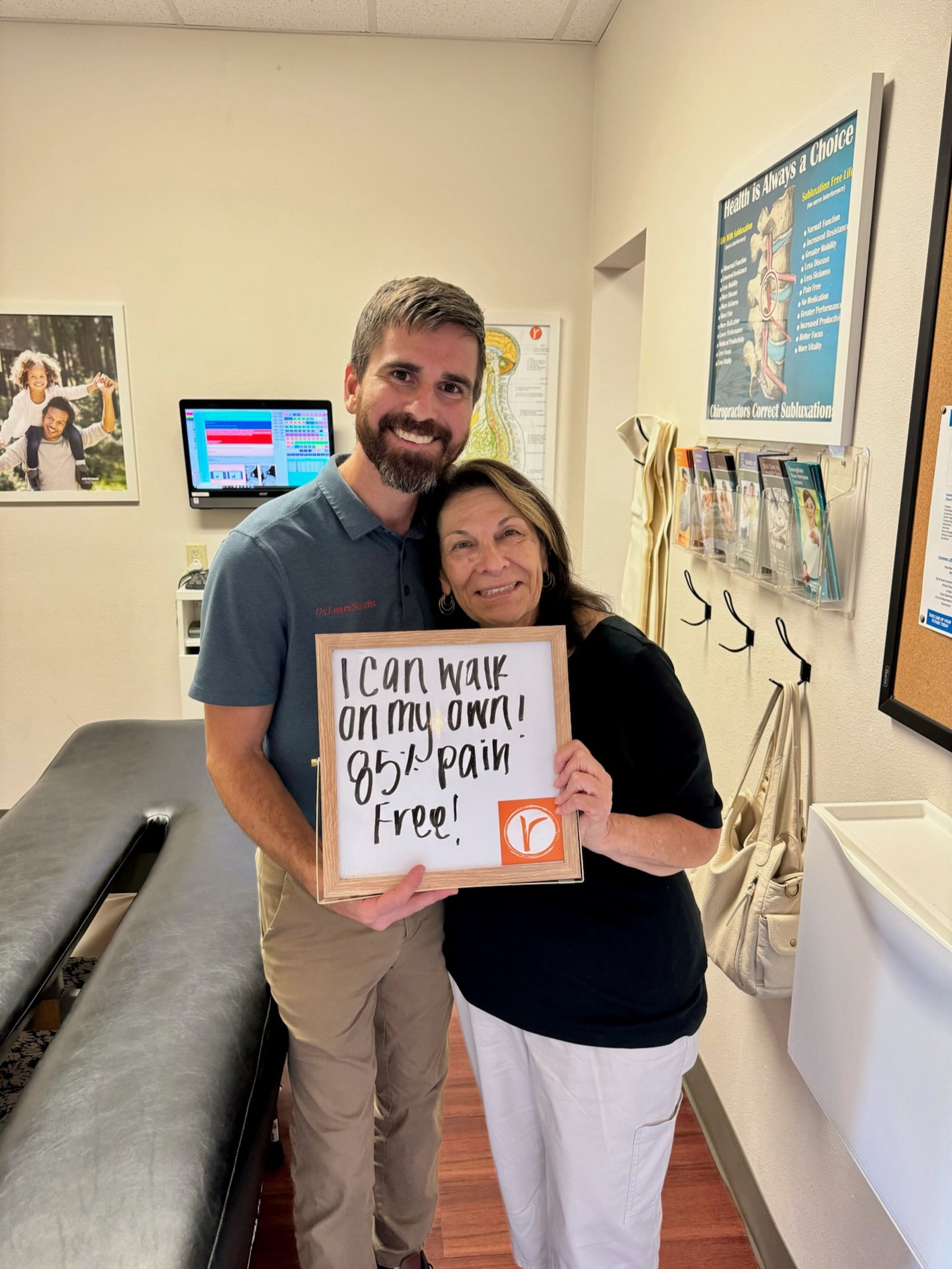 Dr. Logan with a patient holding a sign reading 'I can walk on my own — 85% pain free!'