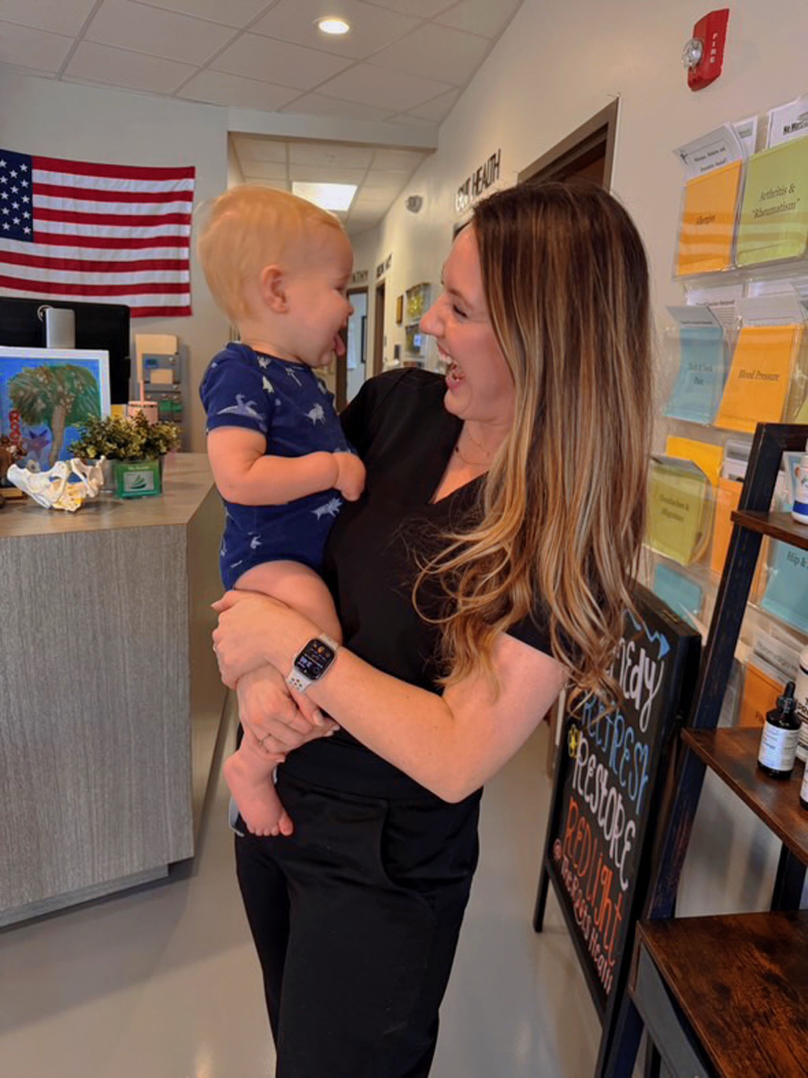 Carly looks tenderly at an infant she's holding in the clinic.